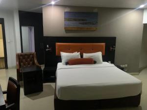 a bedroom with a large white bed and a chair at Oakspring Hotel and Luxury Suites in Lagos