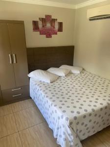 a bedroom with a bed with white sheets and pillows at Residencial Cecilia Cruz in Bombinhas