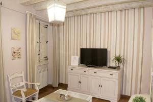 un salon avec une télévision sur un meuble blanc dans l'établissement Apartamenticos Plaza Las Armas II, à Saragosse