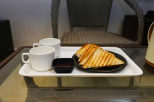 Hotel Sunlight Inn في نيودلهي: صينية بيضاء مع صحن من الخبز المحمص وكوبين
