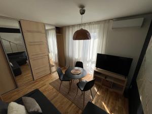 a living room with a television and a table and chairs at Apartament Sołtysowska- garaż bezpłatny in Kraków