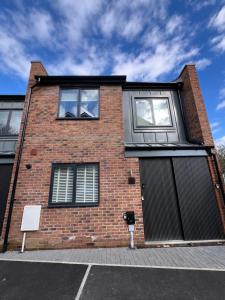 ein Backsteingebäude mit zwei Fenstern und einem Tor in der Unterkunft Barley View Luxury Home in Bristol