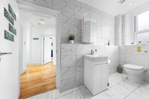 a white bathroom with a toilet and a sink at Stunning apartment in Kings Cross sleeps 10 in London