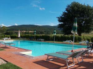 a large swimming pool with benches and umbrellas at Apartment in Casole d'Elsa - Toskana 24073 in Casole dʼElsa