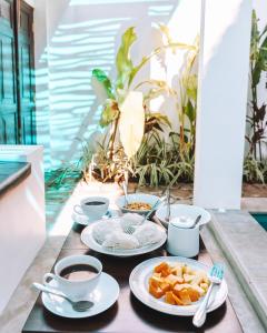 a table with plates of food and cups of coffee at Private Pool Cabanas AC - Angam Villas Hikkaduwa in Hikkaduwa