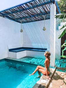 a woman sitting on the edge of a swimming pool at Private Pool Cabanas AC - Angam Villas Hikkaduwa in Hikkaduwa