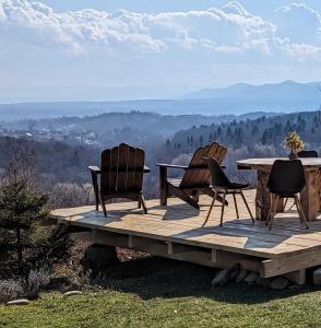 3 sillas y una mesa en una terraza de madera con vistas en Vasanna en Kosiv