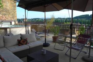 patio con sofá, sombrilla y bañera de hidromasaje en Les Terrasses Dorées - Chambres d'hôtes de charme & Jacuzzi, en Châtillon