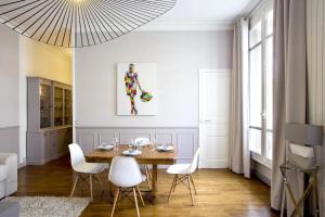a dining room with a wooden table and white chairs at Appartement Caumartin Lafayette in Paris