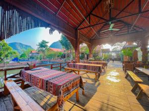 a restaurant with wooden tables and benches with mountains in the background at Trang An Quynh Trang Happy Homestay & Garden in Ninh Binh