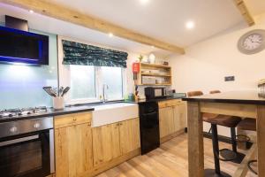 a kitchen with wooden cabinets and a large window at The Piggery at Little Pig in Bude