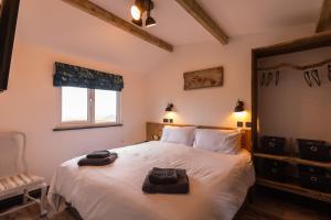 a bedroom with a bed with white sheets and a window at The Piggery at Little Pig in Bude