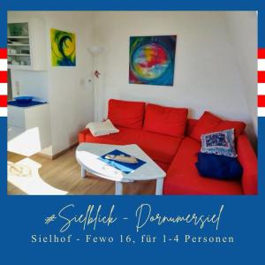 un soggiorno con divano rosso e tavolo di FeWo Sielhof 16 Dornumersiel a Dornumersiel
