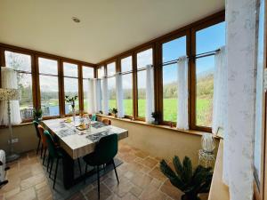 uma sala de jantar com mesa, cadeiras e janelas em Quai Du Val, A Stunning Property With River View em Léhon