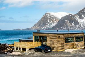 Lyngværet的住宿－Nydelig hytte i unike Lofoten i nærheten av Henningsvær!，前面有停车位的房子
