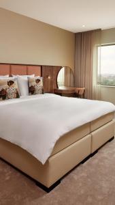 uma grande cama branca num quarto com uma janela em Van der Valk Hotel Delft A4 em Den Hoorn