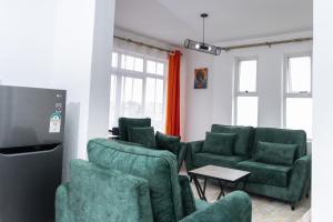 sala de estar con sillas verdes y TV de pantalla plana en Anga Nest a chic One-Bedroom Ngong Road, en Nairobi