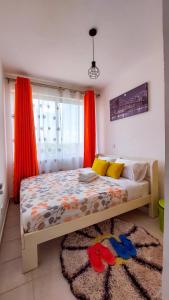 a bedroom with a bed with orange curtains and a rug at Anga Nest a chic One-Bedroom Ngong Road in Nairobi