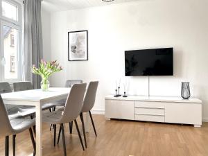 a white dining room with a white table and a tv at *Ferienwohnung in Schwarzwald Villa für 6 Pers.* in Furtwangen
