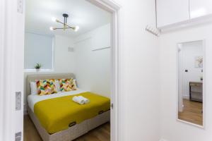 - une chambre avec un lit et une couverture jaune dans l'établissement City Centre One Bedroom Apartment Next to Station, Newly Renovated, à Londres
