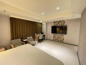 um quarto de hotel com uma cama e uma televisão de ecrã plano em 新仕飯店-New City Hotel em Taipei
