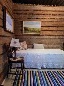 a bedroom with a bed and a lamp on a chair at Villa Miilia maalaismajoitus ja spa in Karijoki