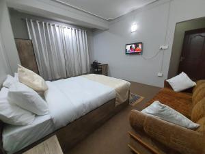 1 dormitorio con cama blanca y sofá en Payong House, en Gangtok