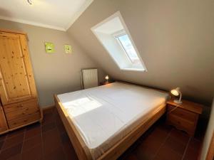 a small bedroom with a bed with a window at Wattblick in Dagebüll