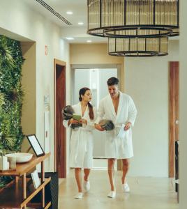 2 persone in vestaglia bianca che camminano in una stanza di Estalagem Santa Iria Hotel & Spa a Tomar