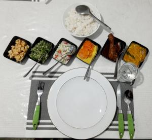 una mesa con un plato blanco y tazones de comida en Green Villa en Nuwara Eliya