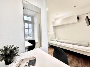 a small white room with a bed and a table at Monteurzimmer ZIMMERzuVERMIETEN Oensingen in Oensingen