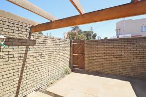 a brick fence with a wooden gate on it at Mikasa Sukasa in Cape Town