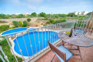 einen Balkon mit einem Tisch und einem Pool in der Unterkunft A lovely 3BR spacious home with Access to POOL by 360 Estates in Qala