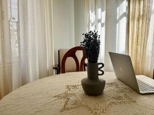 una mesa con ordenador portátil y un jarrón con flores en Ayvalık Old Town, Terrace Home with Sea View, en Ayvalık