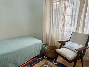 1 dormitorio con silla, cama y ventana en Ayvalık Old Town, Terrace Home with Sea View, en Ayvalık
