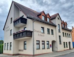biały budynek z czarnymi balkonami przy ulicy w obiekcie Pension Schmidt w mieście Bad Kösen