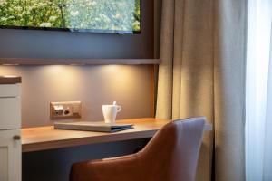 a desk with a chair and a television on a wall at Hotel Du Nord in Interlaken +71 photos
