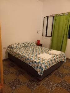 Cama en habitación con cortina verde en La casita de Aitana en Pergamino