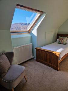 a bedroom with a bed and a chair and a window at Croft 17 in Ullapool