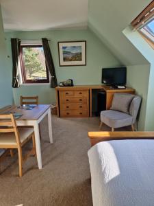 a bedroom with a desk and a table and a chair at Croft 17 in Ullapool