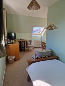 a bedroom with a bed and a desk and a tv at Croft 17 in Ullapool
