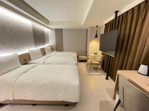 台北市にある新仕飯店-New City Hotelのベッド2台、薄型テレビが備わるホテルルームです。