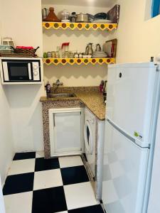 una cucina con frigorifero bianco e pavimento a scacchi di Dar Beldi a Marrakech