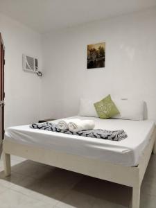 Una cama con sábanas blancas y toallas. en Moalboal Beach Front Hotel en Moalboal