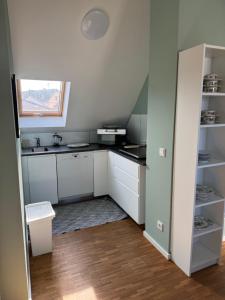 una pequeña cocina con armarios blancos y una ventana en Wohnen am Seebach II, en Westhofen