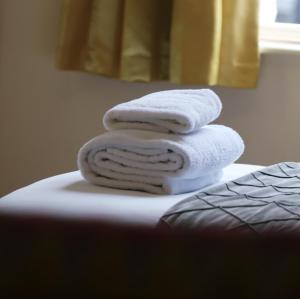a pile of towels sitting on top of a bed at The George Inn in Windsor