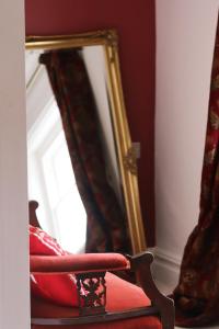 einem roten Stuhl vor einem Spiegel in der Unterkunft The George Inn in Windsor