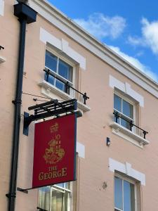 a red sign on the side of a building at The George Inn in Windsor