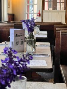 una mesa con flores púrpuras en un jarrón. en The George Inn en Windsor