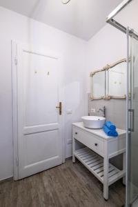 uma casa de banho branca com um lavatório e um espelho em Giardino al Mare em Forte dei Marmi